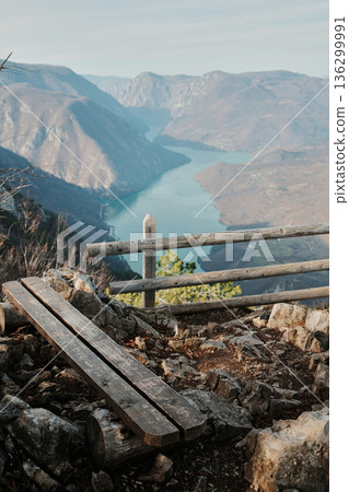 Wooden bench and fence on rocky viewpoint overlooking Drina River canyon and Perucac Lake in Tara National Park, Serbia. Mountain landscape with steep slopes and water 136299991