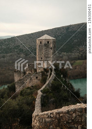 Stone wall path leading to the main tower of Pocitelj Fortress above the Neretva River in Bosnia and Herzegovina. Medieval fortifications and nature express strength and timeless travel concept Stone wall path leading to the main tower of Pocitelj Fortress above the Neretva River in Bosnia and Herzegovina. Medieval fortifications and nature express strength and timeless travel concept 136300451