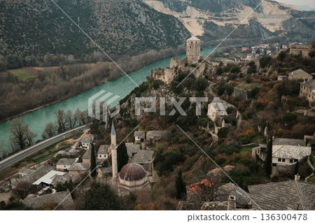 Elevated view of Pocitelj Fortress with medieval stone tower above the Neretva River and historic village houses along a rocky hillside in Bosnia and Herzegovina Elevated view of Pocitelj Fortress with medieval stone tower above the Neretva River and historic village houses along a rocky hillside in Bosnia and Herzegovina 136300478
