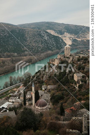 Elevated view of Pocitelj Fortress with medieval stone tower above the Neretva River and historic village houses along a rocky hillside in Bosnia and Herzegovina Elevated view of Pocitelj Fortress with medieval stone tower above the Neretva River and historic village houses along a rocky hillside in Bosnia and Herzegovina 136300481