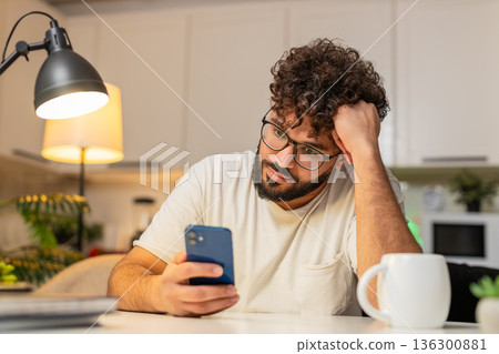 Arabian man bored scrolls smartphone news at night stressed demotivated sighs needs break from news Arabian man bored scrolls smartphone news at night stressed demotivated sighs needs break from news 136300881