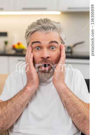 Middle-aged man grabs cheeks says wow happy surprise after positive good news joyful reaction Middle-aged man grabs cheeks says wow happy surprise after positive good news joyful reaction 136300899