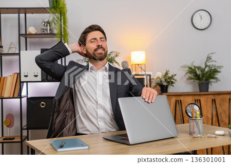 Middle-aged businessman finishes final report powers down laptop closes lid stretches smiles relaxed Middle-aged businessman finishes final report powers down laptop closes lid stretches smiles relaxed 136301001