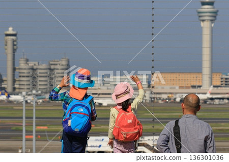 一名兒童在羽田機場的觀景台上向起飛的飛機揮手致意。 136301036
