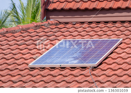 A Solar Panel Installed on a Red-Tiled Roof: Photovoltaic Cells Converting Sunlight into Electricity, a Key Renewable Energy Source for Sustainable Home Power. High quality photo 136301039