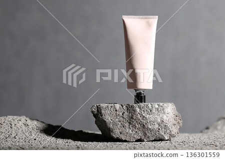 Pink cosmetic tube at natural rock podium at grey background , visuals for beauty and cosmetic product . 136301559