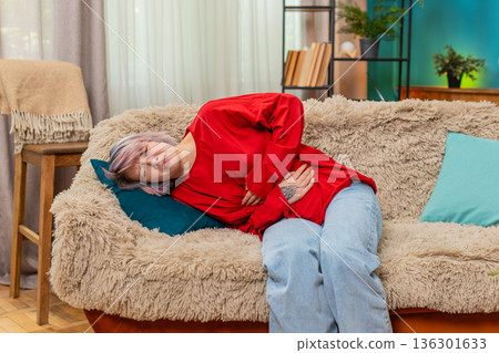 Woman experiencing stomach pain holding belly, uncomfortable painful facial expression showing ache Woman experiencing stomach pain holding belly, uncomfortable painful facial expression showing ache 136301633