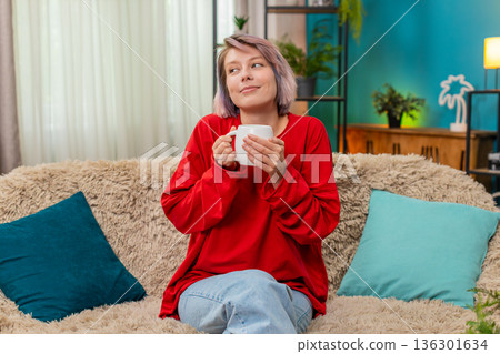 Woman enjoying drinking coffee sits comfortably on couch relaxed satisfied calm leisure expression 136301634