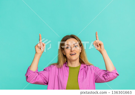 Woman pointing up with serious expression drawing attention to important thing or key information 136301663