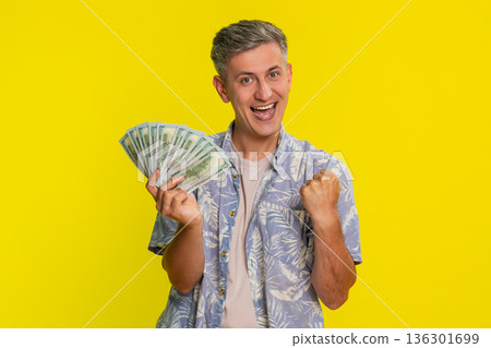 Adult man with joy waving and holding dollars cash celebrating win in lottery game or jackpot Adult man with joy waving and holding dollars cash celebrating win in lottery game or jackpot 136301699