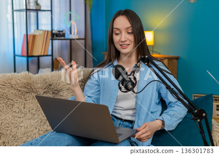 Woman blogger happily recording podcast vlog on sofa actively gesturing telling interesting story Woman blogger happily recording podcast vlog on sofa actively gesturing telling interesting story 136301783