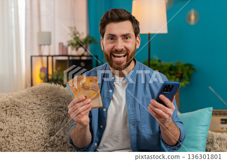Man checking balance on smartphone, excited about received money, celebrating lottery or game win Man checking balance on smartphone, excited about received money, celebrating lottery or game win 136301801