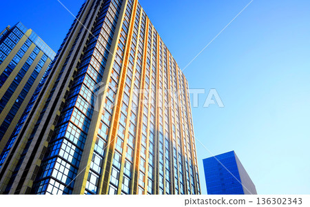 Glass building in sunset. Facade of new modern business office building. Glass building facade Glass building in sunset. Facade of new modern business office building. Glass building facade 136302343