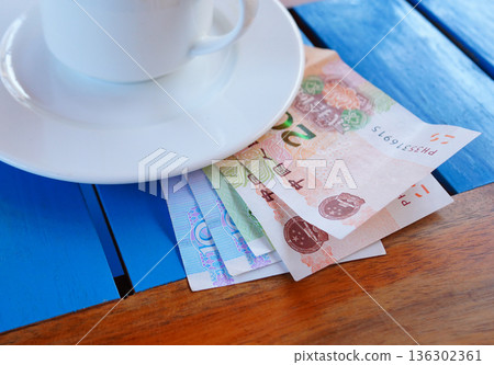 Coffee cup on table with yuan bill money in cafe. Payment coffee drink on breakfast. Yuan biill 136302361