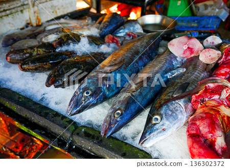Fish sale at local market. Fresh seafood in ice on counter in grocery store. Fish sale at local market. Fresh seafood in ice on counter in grocery store. 136302372