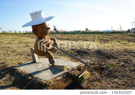 A wooden doll plowing a field set up on a vast plot of land in a rural town 136302807