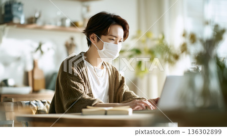 /* 室內工作場景，一名男子正在專心工作或學習，同時採取措施緩解花粉症症狀 */ 136302899