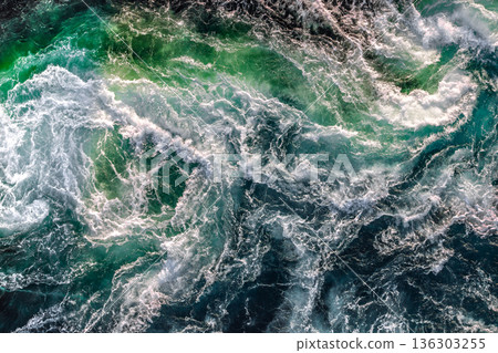 Blue waves of water of the river and the sea meet each other during high tide and low tide. 136303255