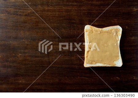 A slice of bread with peanut butter on a table background viewed from above 136303490