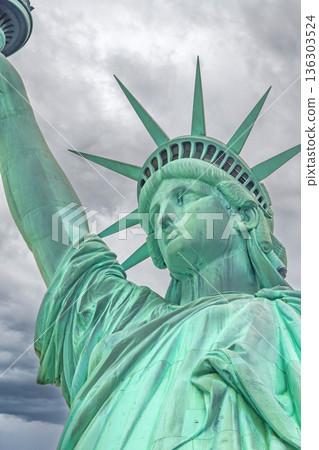 Statue of Liberty closeup with dramatic sky in background. Statue of Liberty closeup with dramatic sky in background. 136303524