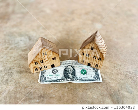 Conceptual image of wooden house models placed on a US dollar bill, representing real estate investment, housing finance, property value, mortgage planning, savings for home ownership, and financial Conceptual image of wooden house models placed on a US dollar bill, representing real estate investment, housing finance, property value, mortgage planning, savings for home ownership, and financial 136304058