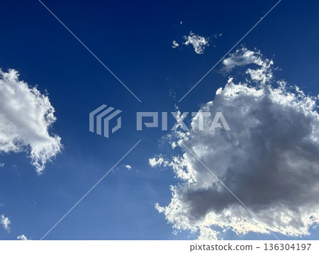 湛藍的天空與潔白的雲朵形成鮮明對比。強烈的陽光穿透雲層,灑下美麗的光輝。 湛藍的天空與潔白的雲朵形成鮮明對比。強烈的陽光穿透雲層,灑下美麗的光輝。 136304197