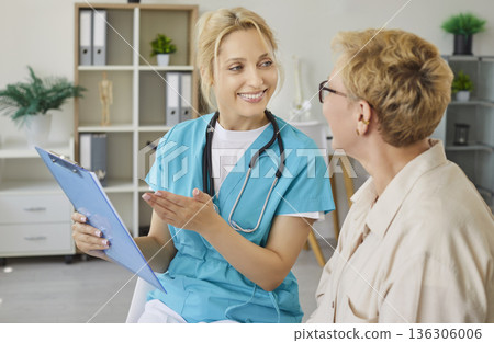 Nurse using clipboard with records to report good health news to senior woman Nurse using clipboard with records to report good health news to senior woman 136306006