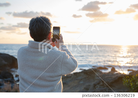 A man shooting the setting sun 136306219