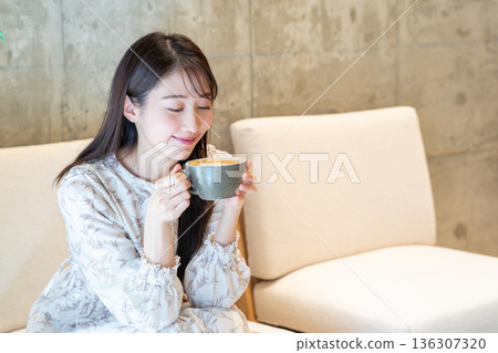 一位女士在咖啡館喝拿鐵咖啡 136307320