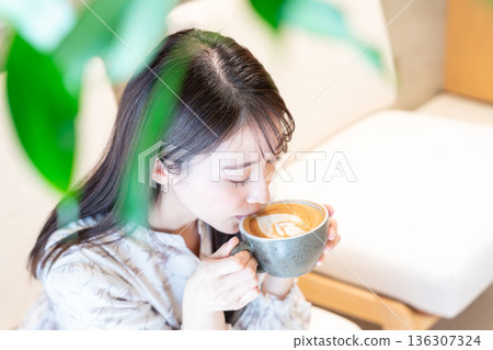 Woman drinking a cafe latte at a cafe Woman drinking a cafe latte at a cafe 136307324