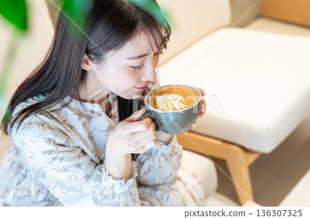 Woman drinking a cafe latte at a cafe Woman drinking a cafe latte at a cafe 136307325