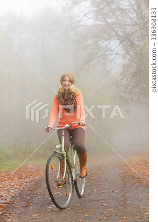 Active woman riding bike in autumn park. 136308131