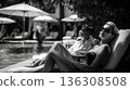 woman lounging poolside wearing sunglasses 136308508