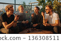 Friends smoking pipes on rooftop terrace 136308511