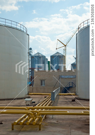 Industrial storage silos and yellow pipeline infrastructure at a manufacturing plant 136308808