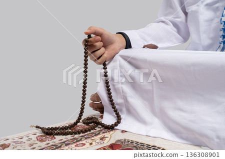Person in traditional dress engaged in spiritual devotion with beads Person in traditional dress engaged in spiritual devotion with beads 136308901