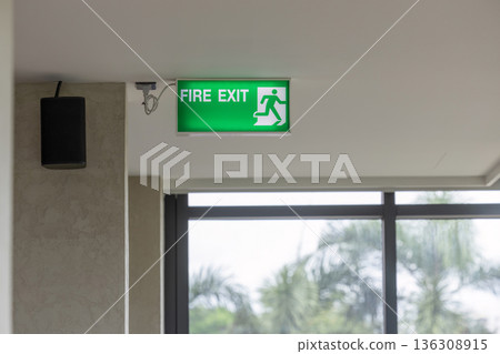 Green emergency exit sign showing the way to escape. Fire exit in the building. 136308915