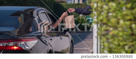 Hand Man in car receiving coffee in drive thru fast food restaurant. 136308980