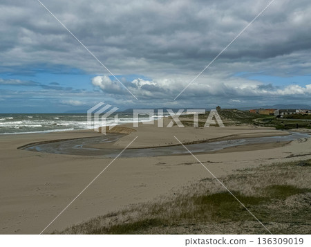 Wide coastal landscape in Povoa de Varzim, Portugal with sandy dunes, river mouth and Atlantic Ocean under dramatic cloudy sky 136309019