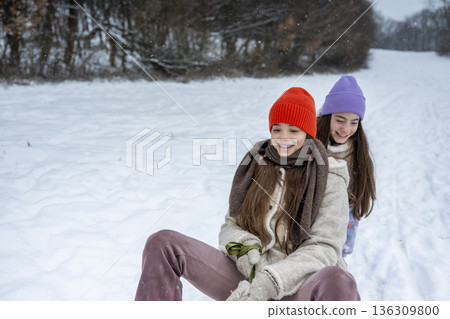 Sisters sledding together and experiencing winter excitement. Sisters sledding together and experiencing winter excitement. 136309800