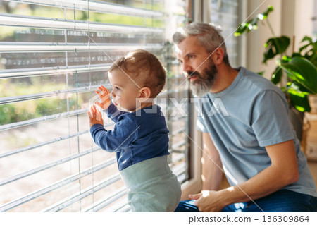 Father with little toddler son looking out of window. 136309864