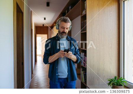 Bearded man listening to music at home. 136309875