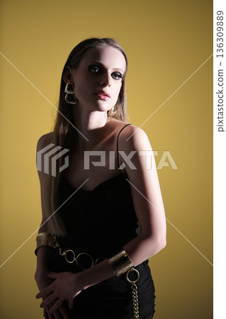 Woman posing wearing statement golden jewelry and black dress 136309889