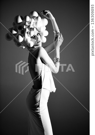 Woman wearing avant-garde headpiece and elegant dress posing Woman wearing avant-garde headpiece and elegant dress posing 136309893