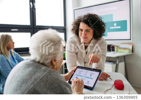 Elderly woman learning digital skills with tutor help. 136309905
