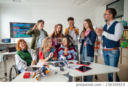 Diverse high school team celebrating teamwork during robotics project. 136309919