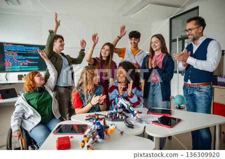 Diverse high school team celebrating teamwork during robotics project. 136309920