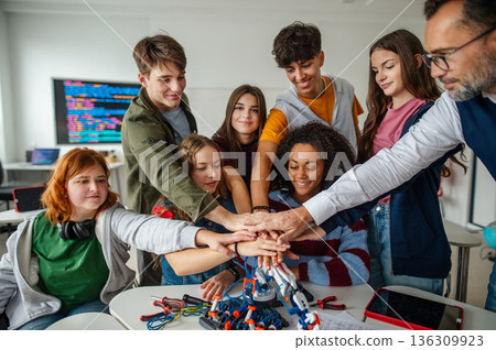 Diverse high school team celebrating teamwork during robotics project. 136309923