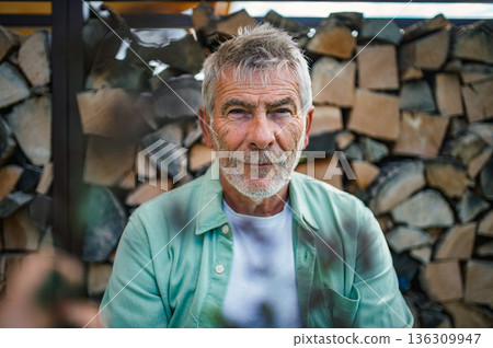 Older man with gray hair posing in front of wooden logs. Older man with gray hair posing in front of wooden logs. 136309947