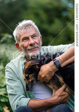 Older man spending quality time with dog, natural setting. 136309950